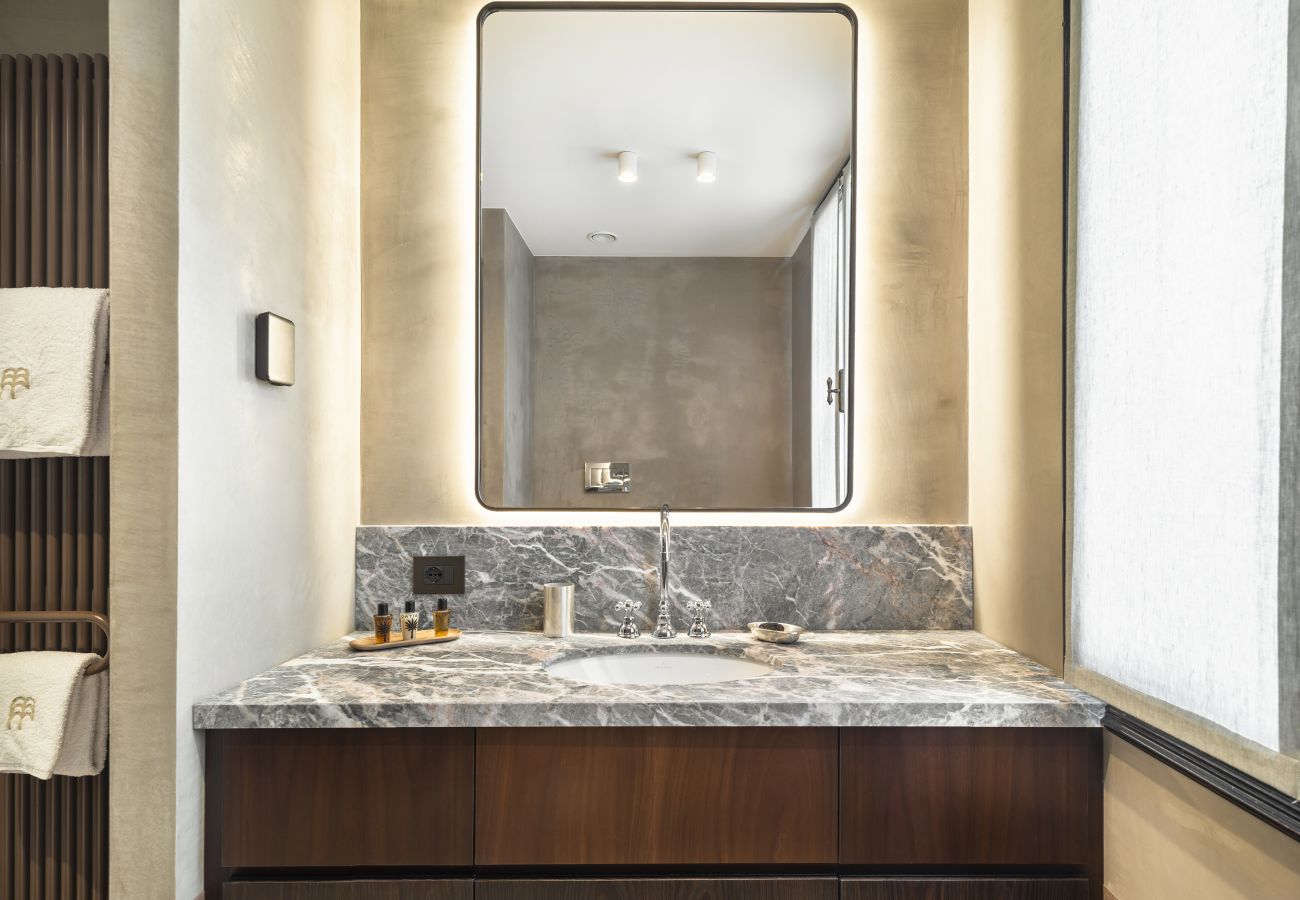 Elegant bathroom with marble sink, backlit mirror and stone cladding in the Artista property